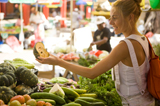 Photo showing a young lady buying produce from a market vendor
